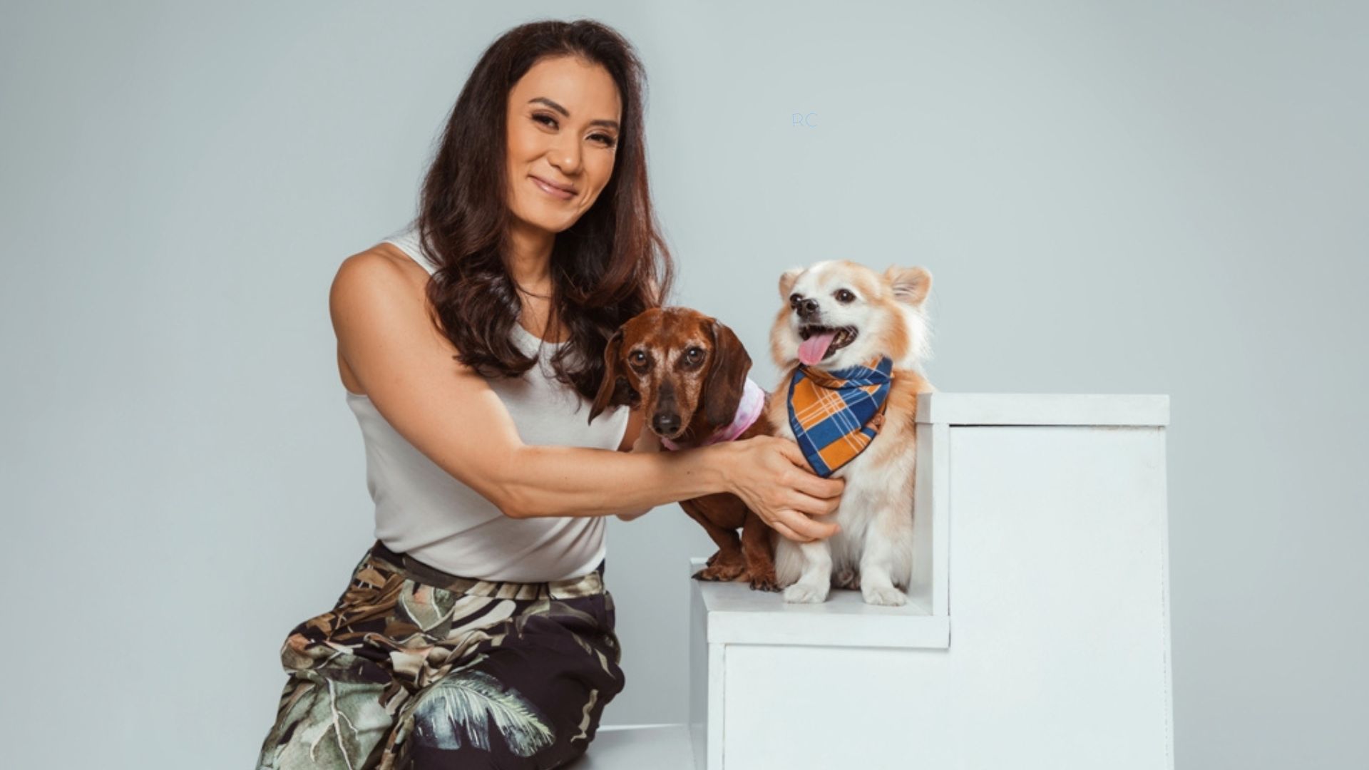Mulher oriental sentada na escada fazendo carinho em um cão