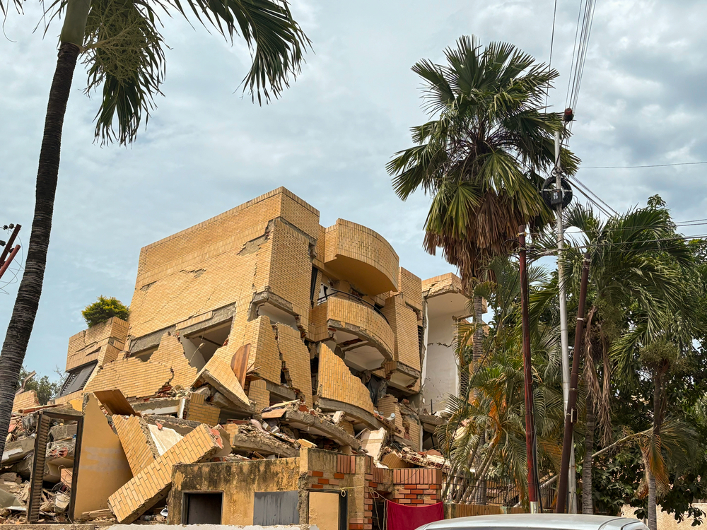 Edifício residencial de tijolos com andares desabados e estrutura severamente rompida após os terremotos na Venezuela.