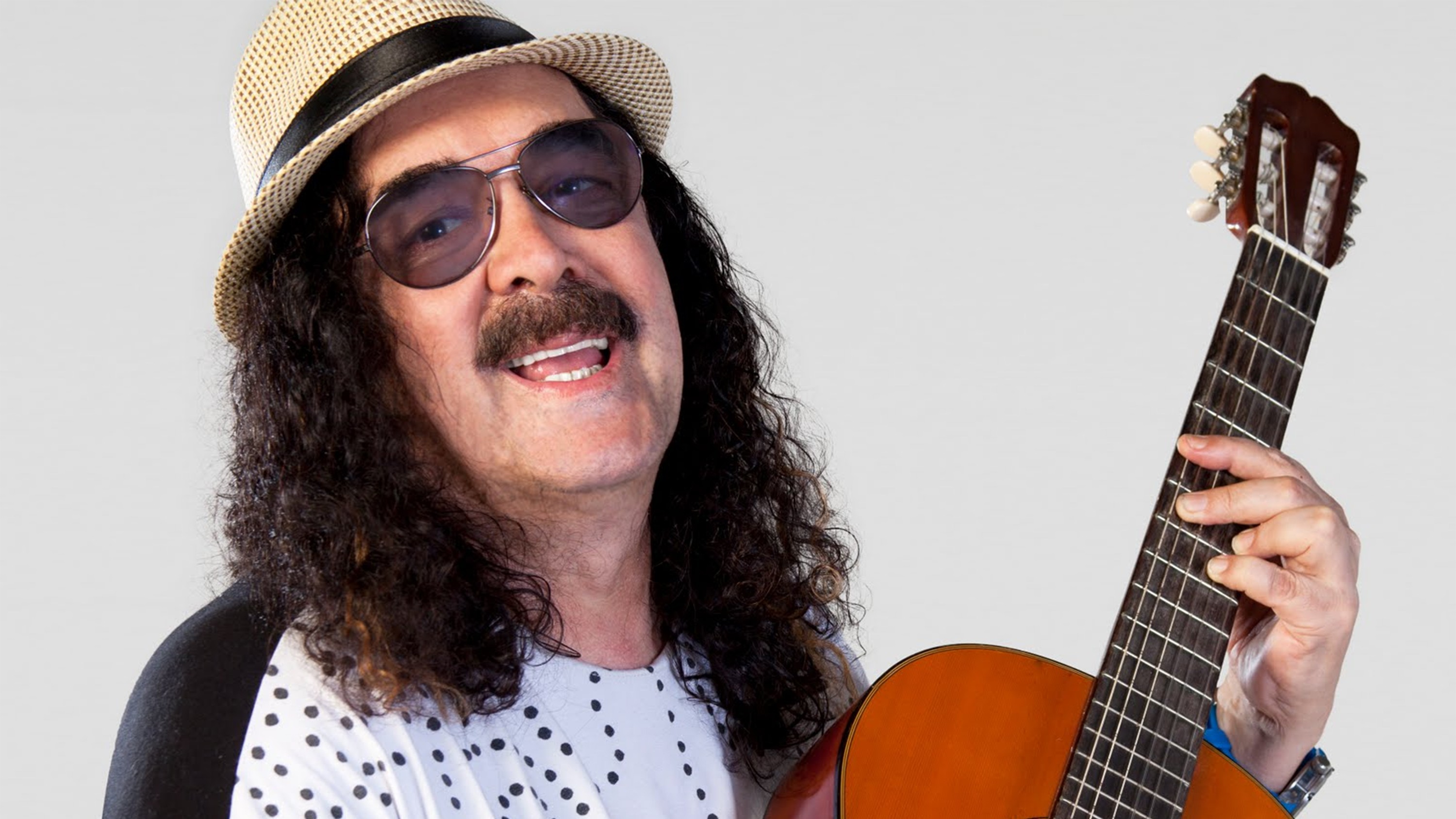 Moraes Moreira usa chapéu, óculos e está segurando violão