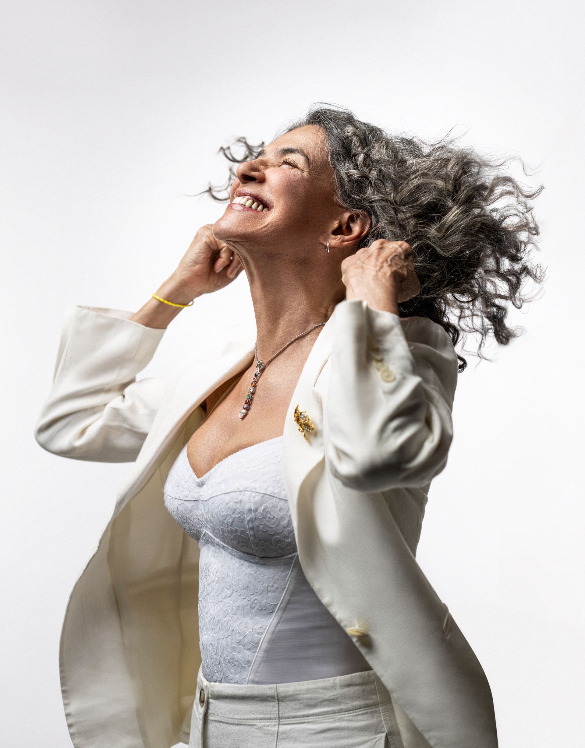 Cantora Simone de terno branco, mexendo nos cabelos e sorrindo