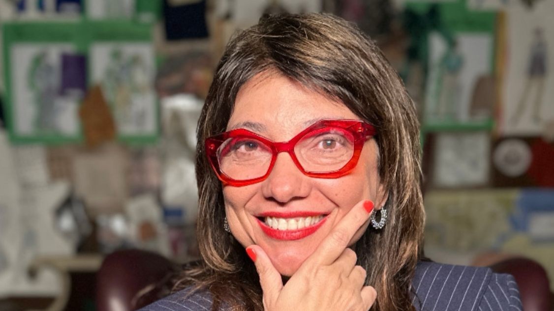 Susanna Lira usa óculos vermelhos e está segurando o rosto com a mão