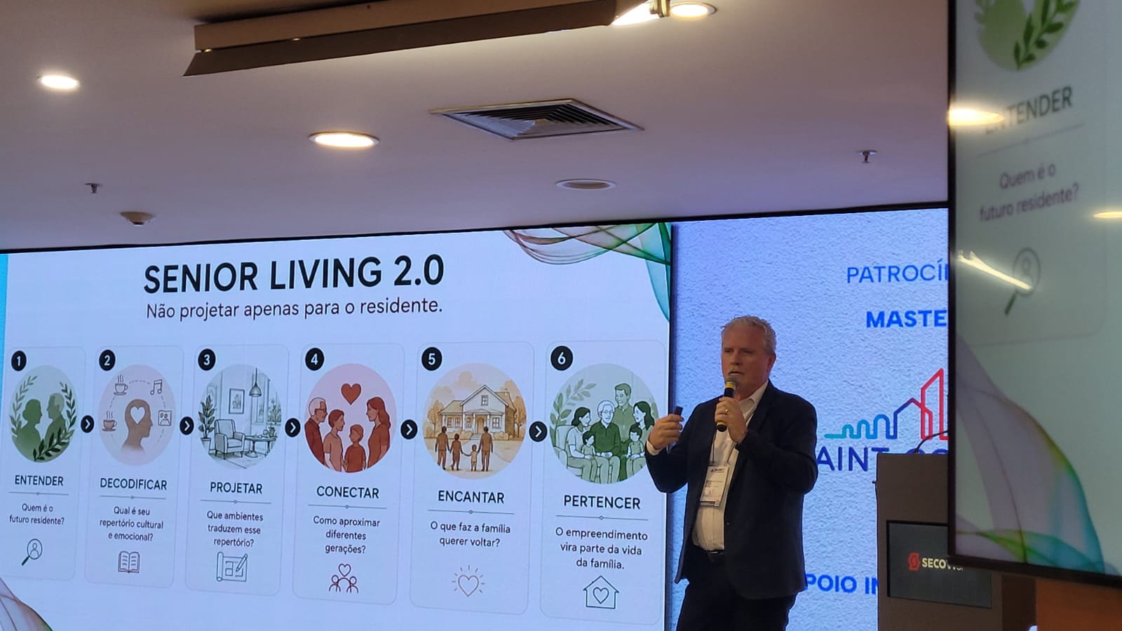 Martin Henkel, homem, branco, em um palco apresentando uma palestra