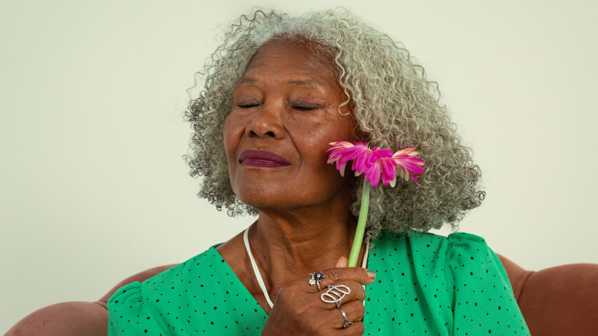 Uma mulher negra idosa posando com uma flor
