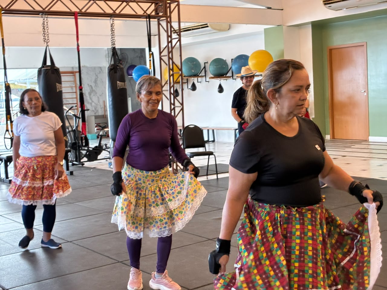 Mulheres idosas de saias coloridas fazem exercícios em arena de boxe para Parkinson