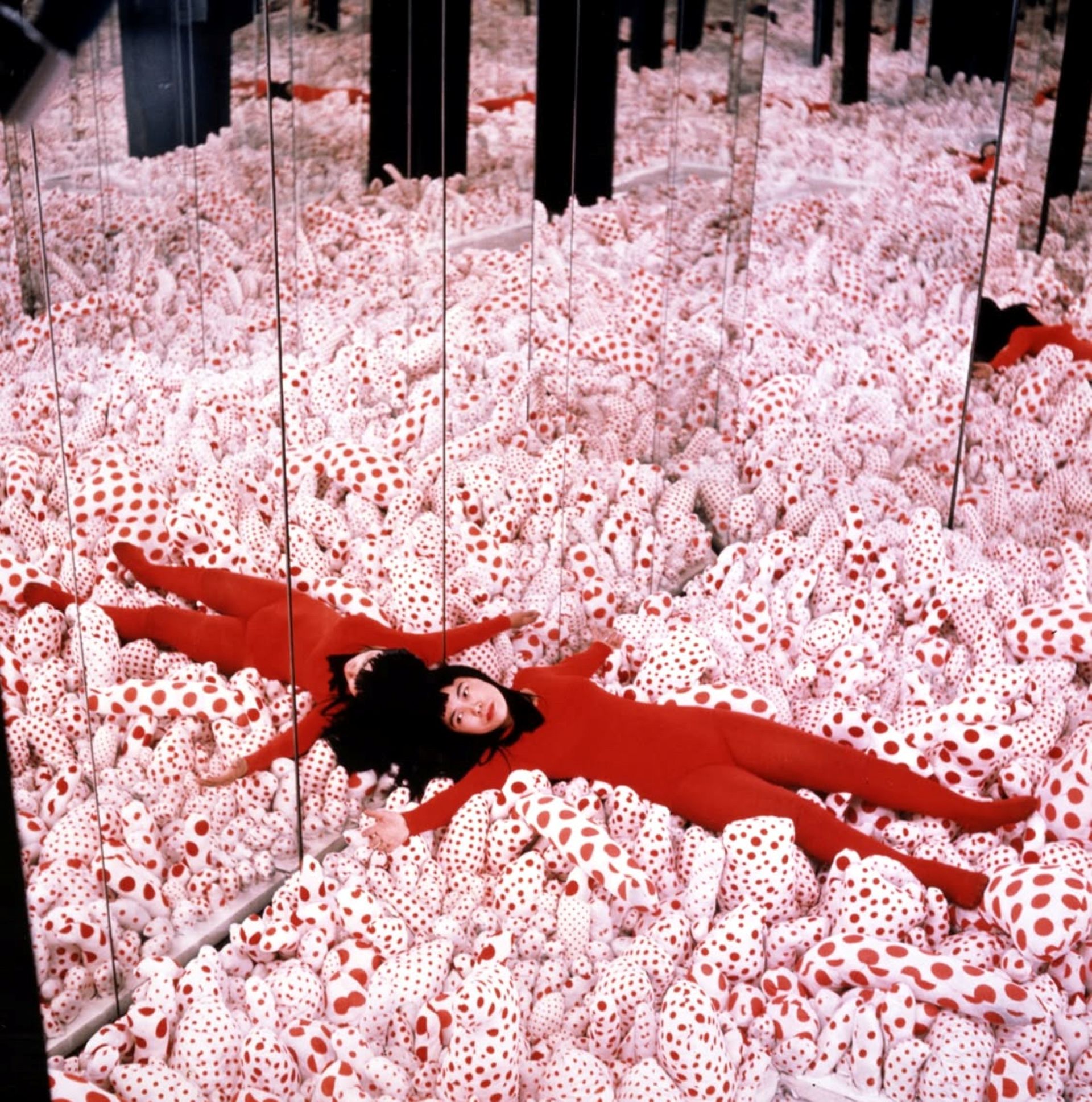 Yayoi Kusama está de vermelho sobre bolas pintadas de bolinhas vermelhas