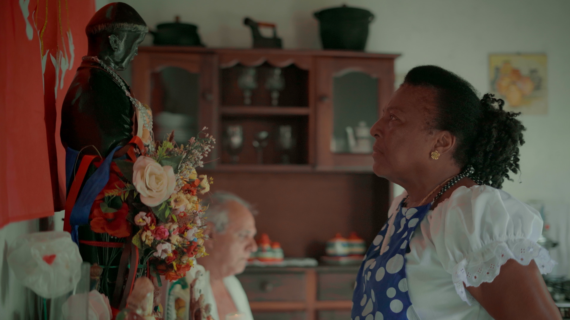 Uma mulher negra olha para uma imagem de santo