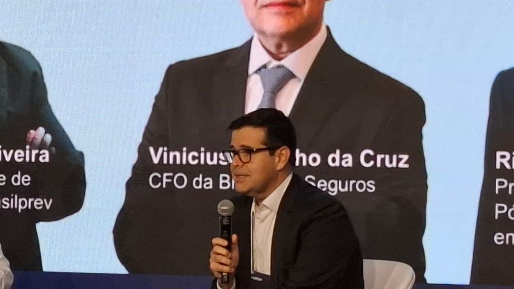 Vinicius da Cruz, homem branco, de óculos cabelos escuros em um palco