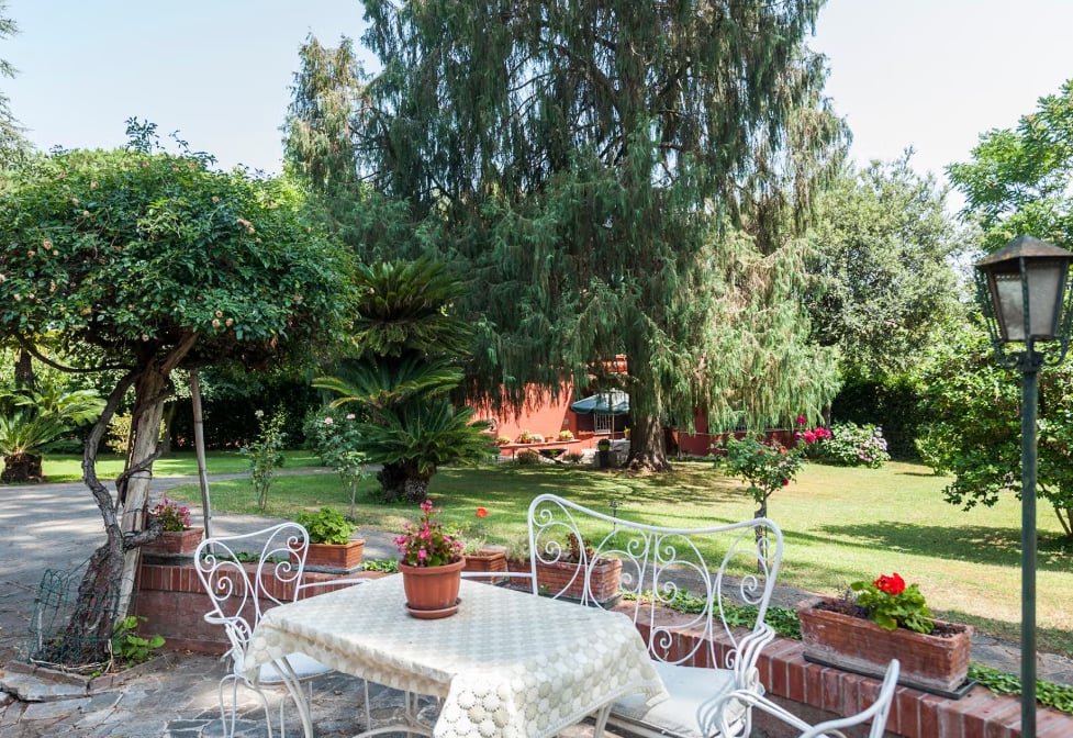 Área externa com muito verde e uma mesa com cadeiras