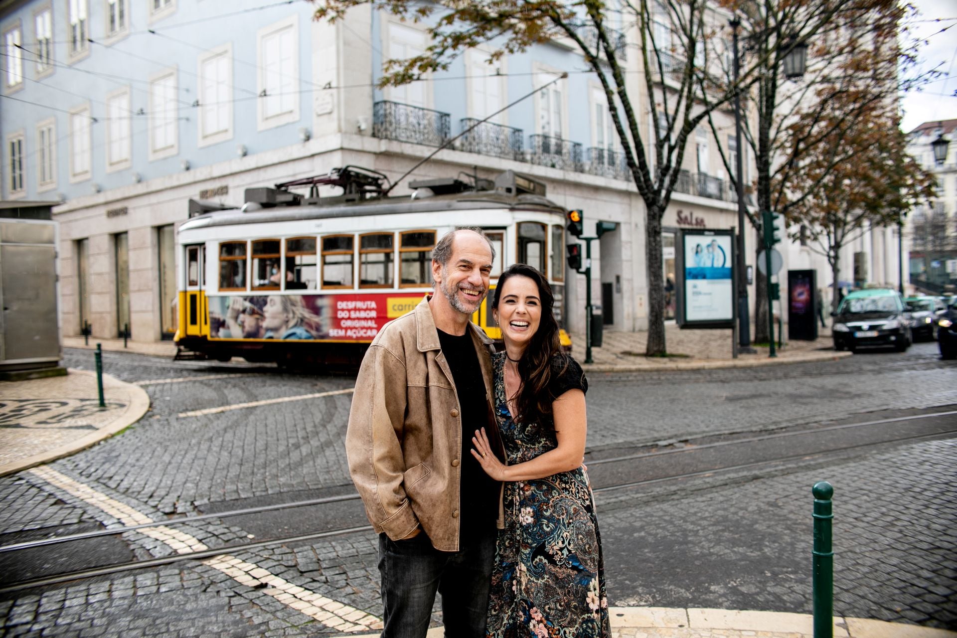 Roberto Bomtempo e Miriam Freeland estão sorrindo, em uma rua